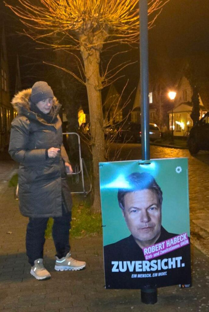 Ricarda Eckert-Hagensen mit einem Plakat von Robert Habeck in Arnis. Auf dem Plakat steht "ZUVERSICHT" - EIn Mensch. Ein Wort.